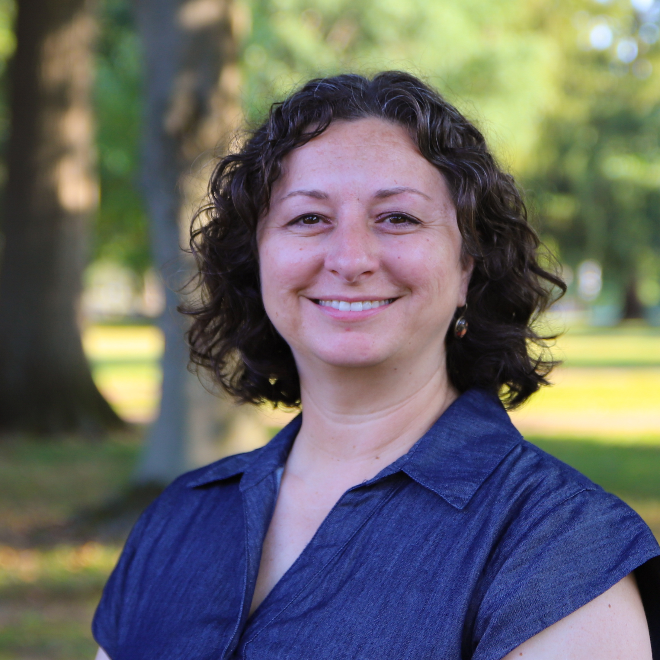 Portrait of Nina Alcorn with a green, natural background.